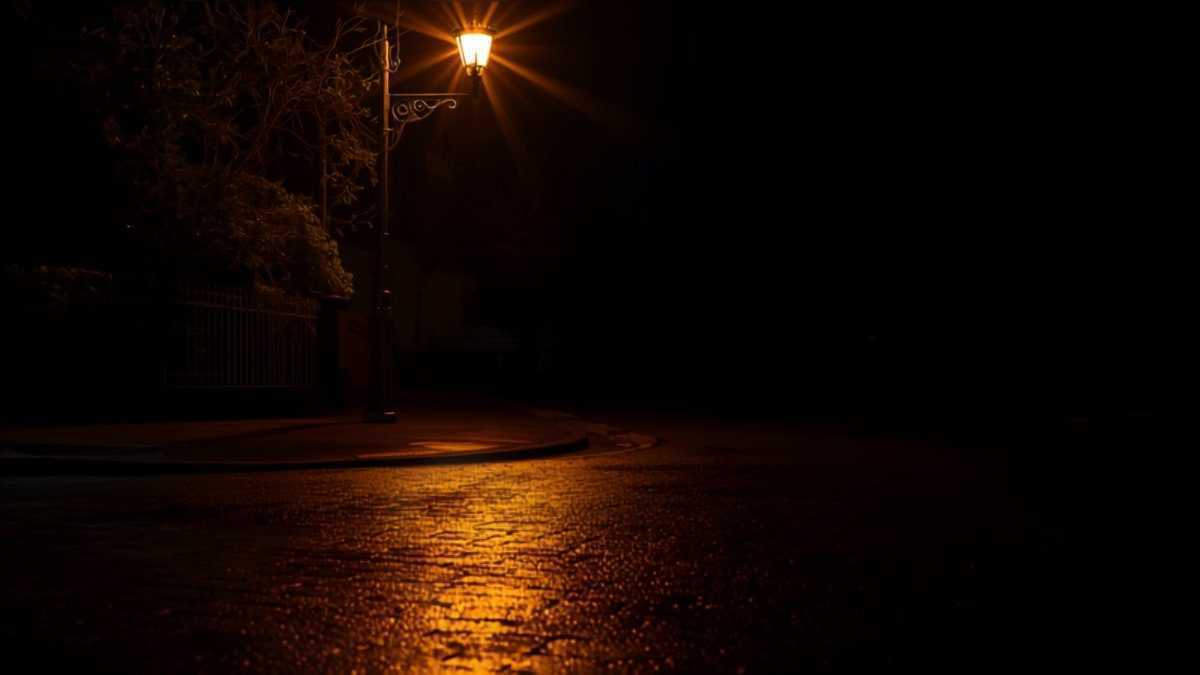 Trottoir désert éclairé par un lampadaire ancien, pavés mouillés